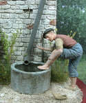 Junger Mann wäscht sich die Füße am Regenbottich